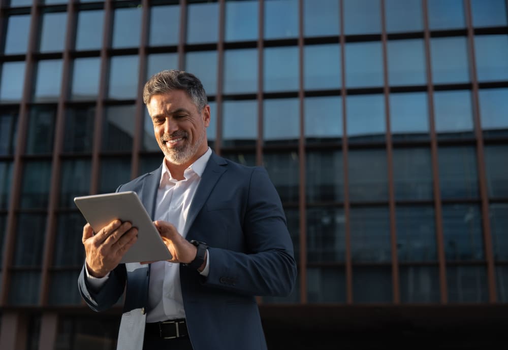 man in suit looking at a laptop outside of an office building