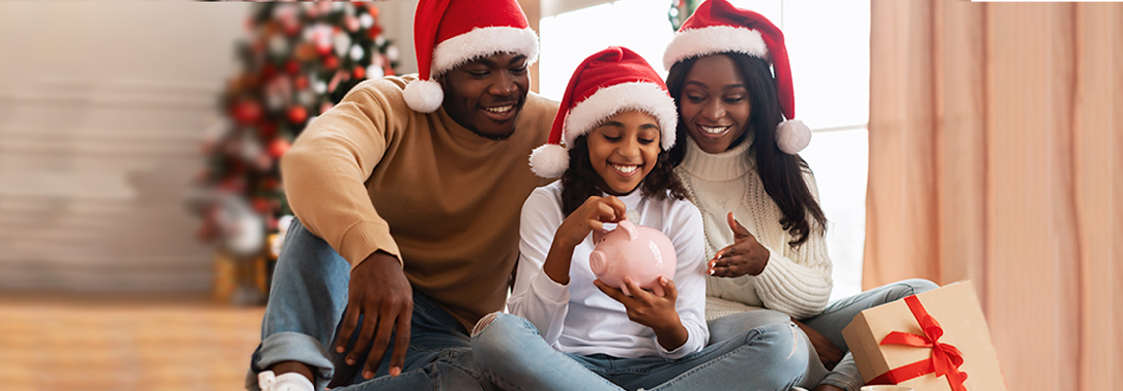 family wearing Santa hats, child holding piggy bank