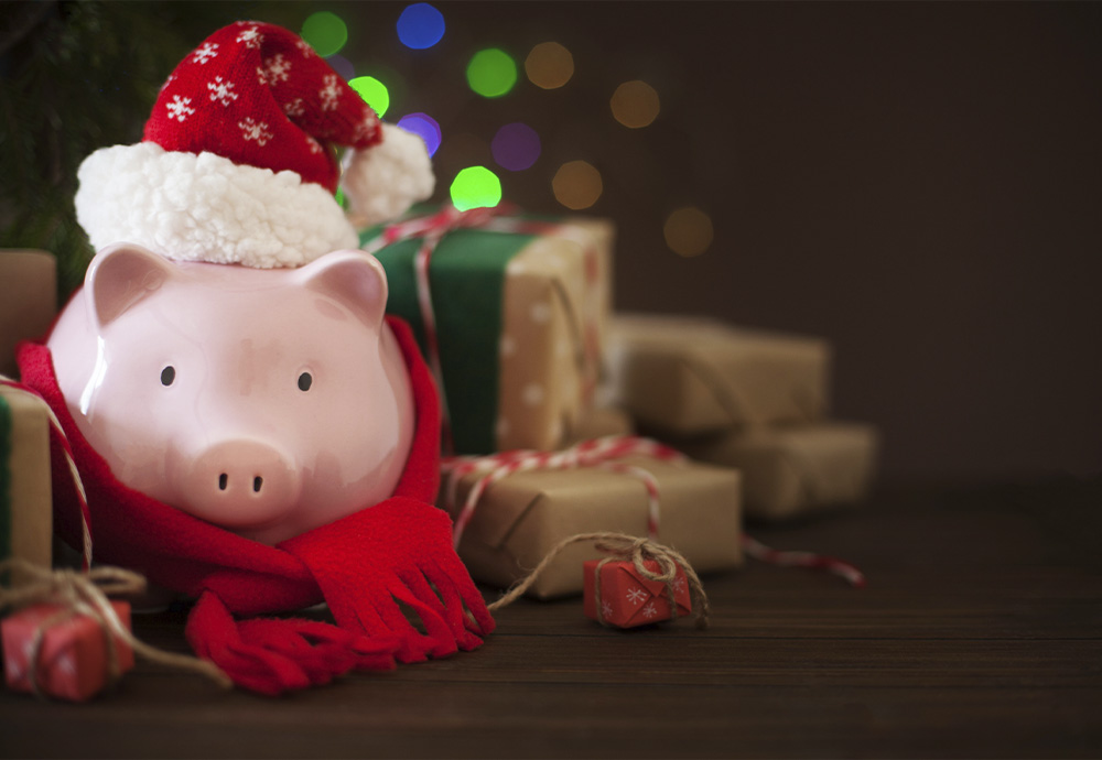 piggy bank wearing a Christmas hat surrounded by presents under a Christmas tree