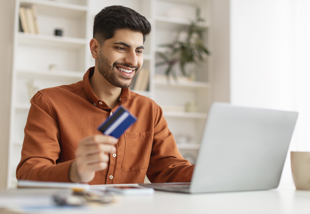 man with debit card looking at laptop