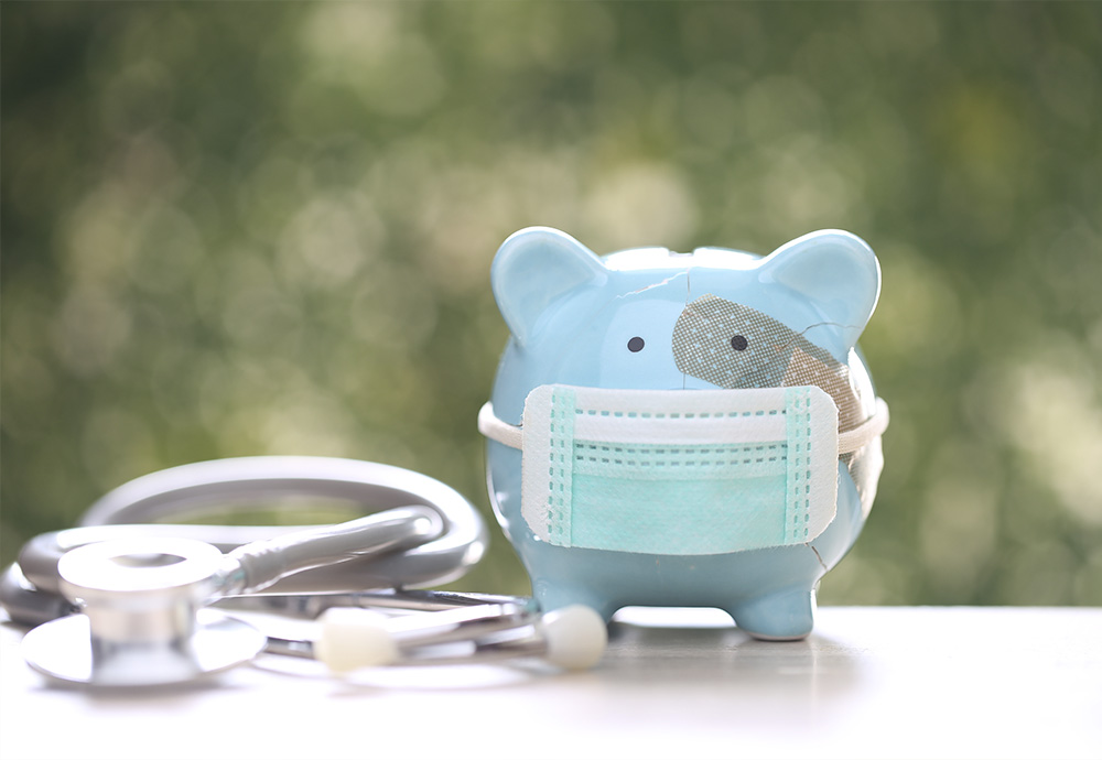 piggy bank with bandage, wearing a mask next to a stethoscope 